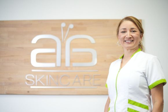 A woman is standing in front of a sign that says a6 skincare