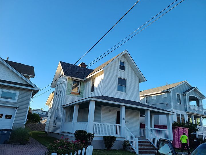A white house with a gray roof and a porch