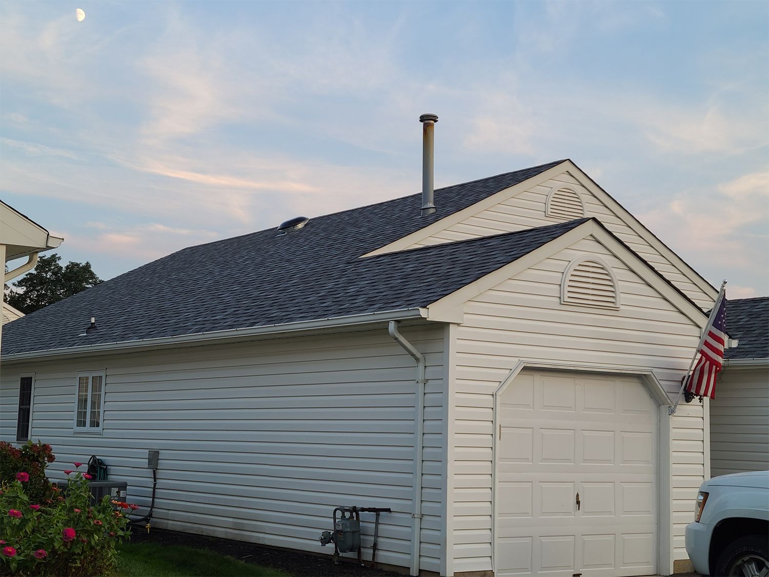 A white house with a blue roof and a truck parked in front of it.