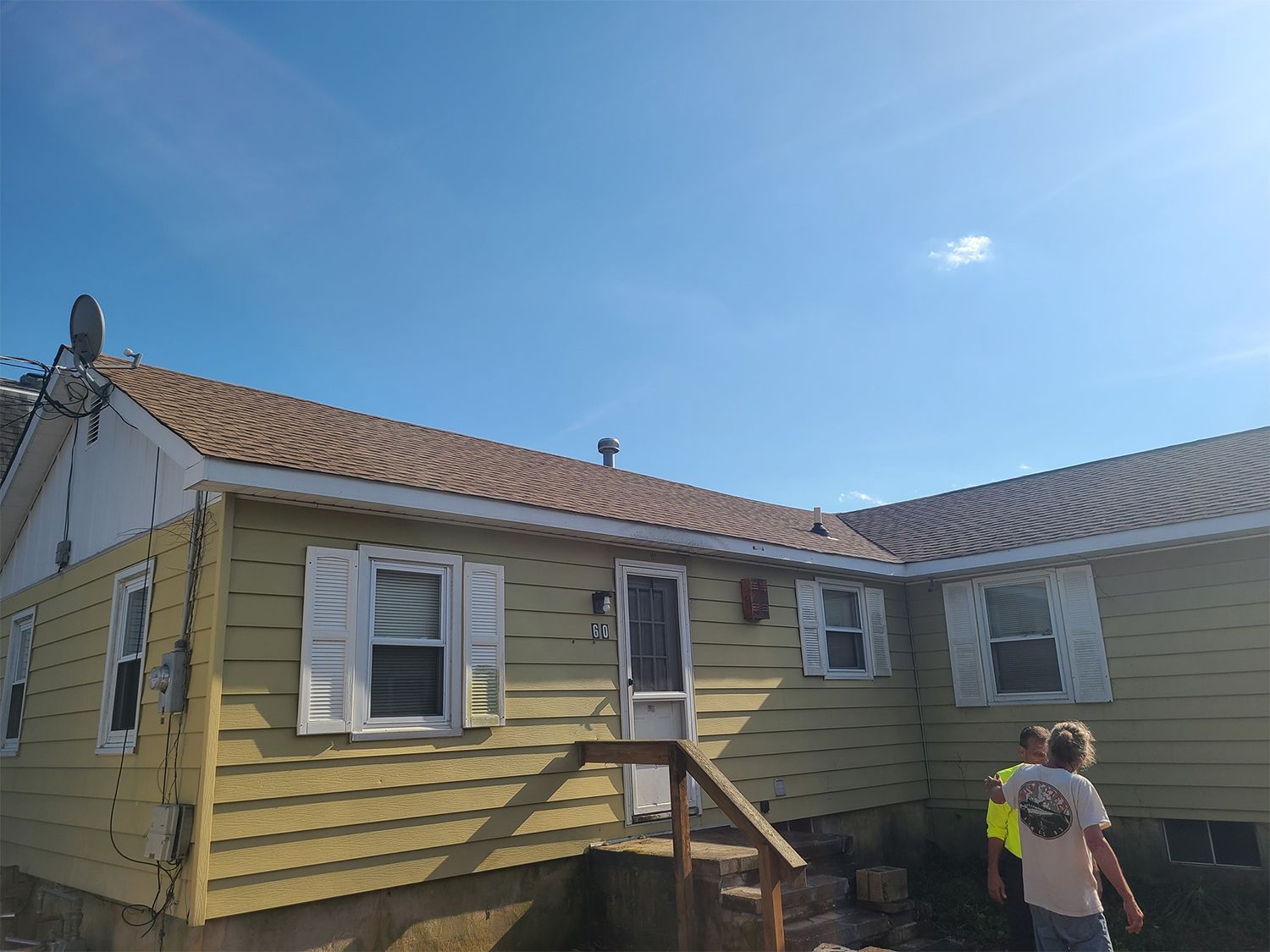 A couple of people are standing in front of a yellow house.