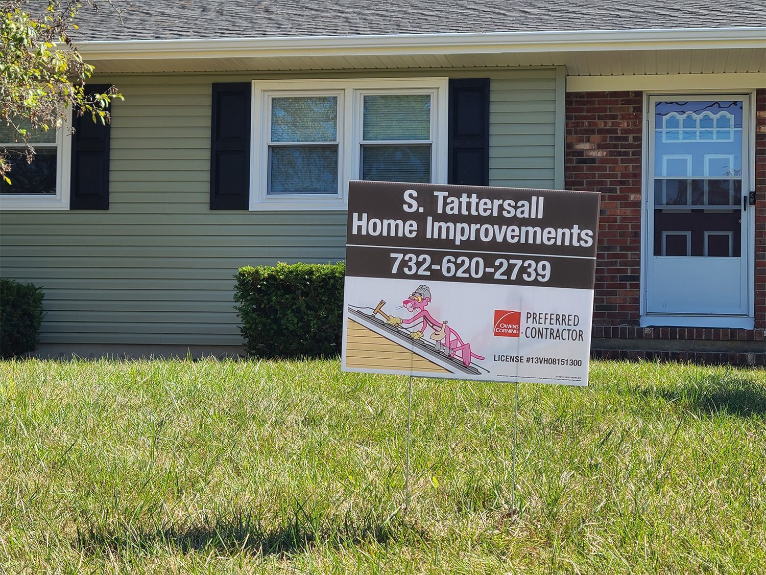 A sign for s. tattersall home improvements is in front of a house