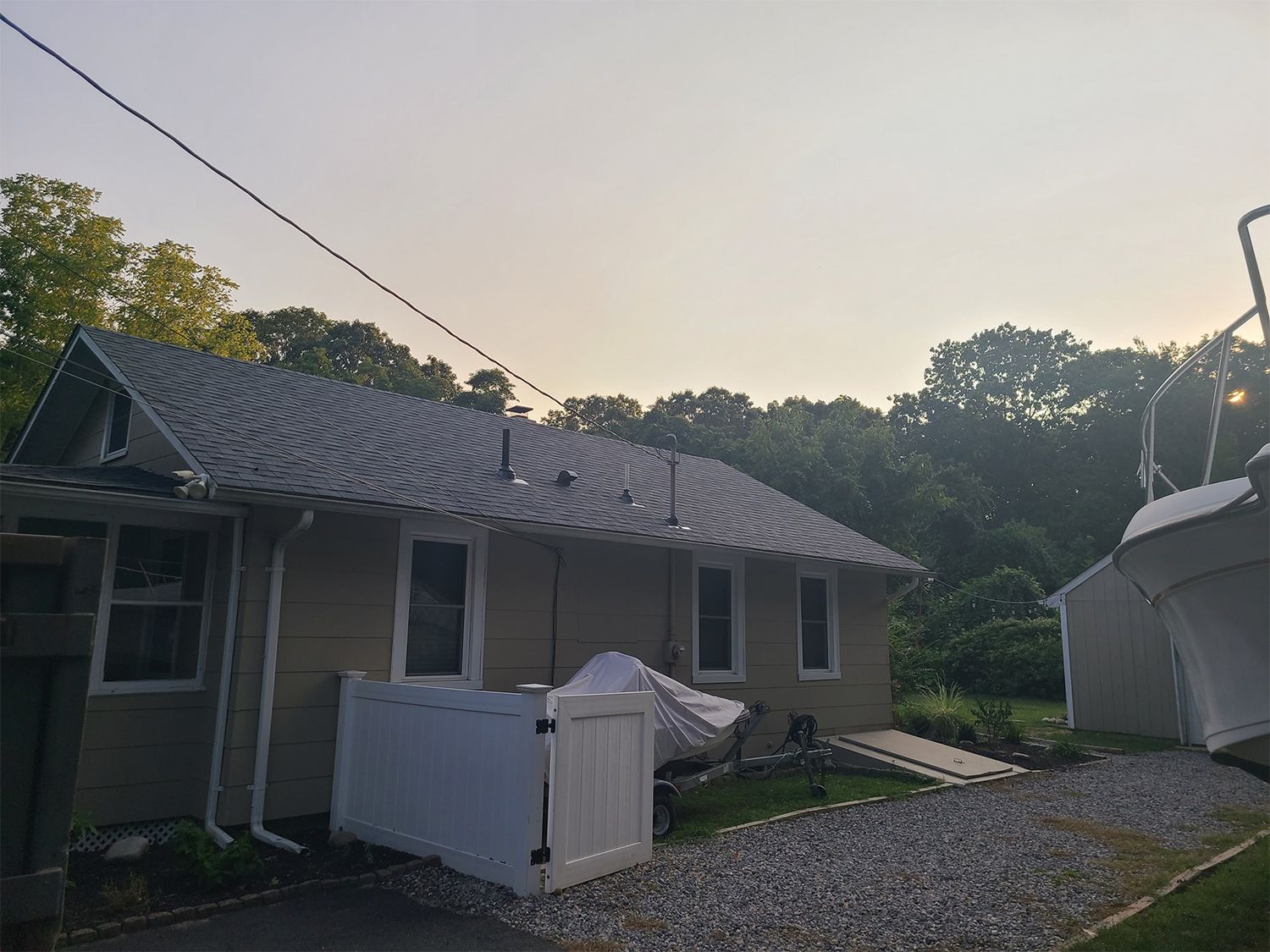 A house with a gray roof and a white fence in front of it.