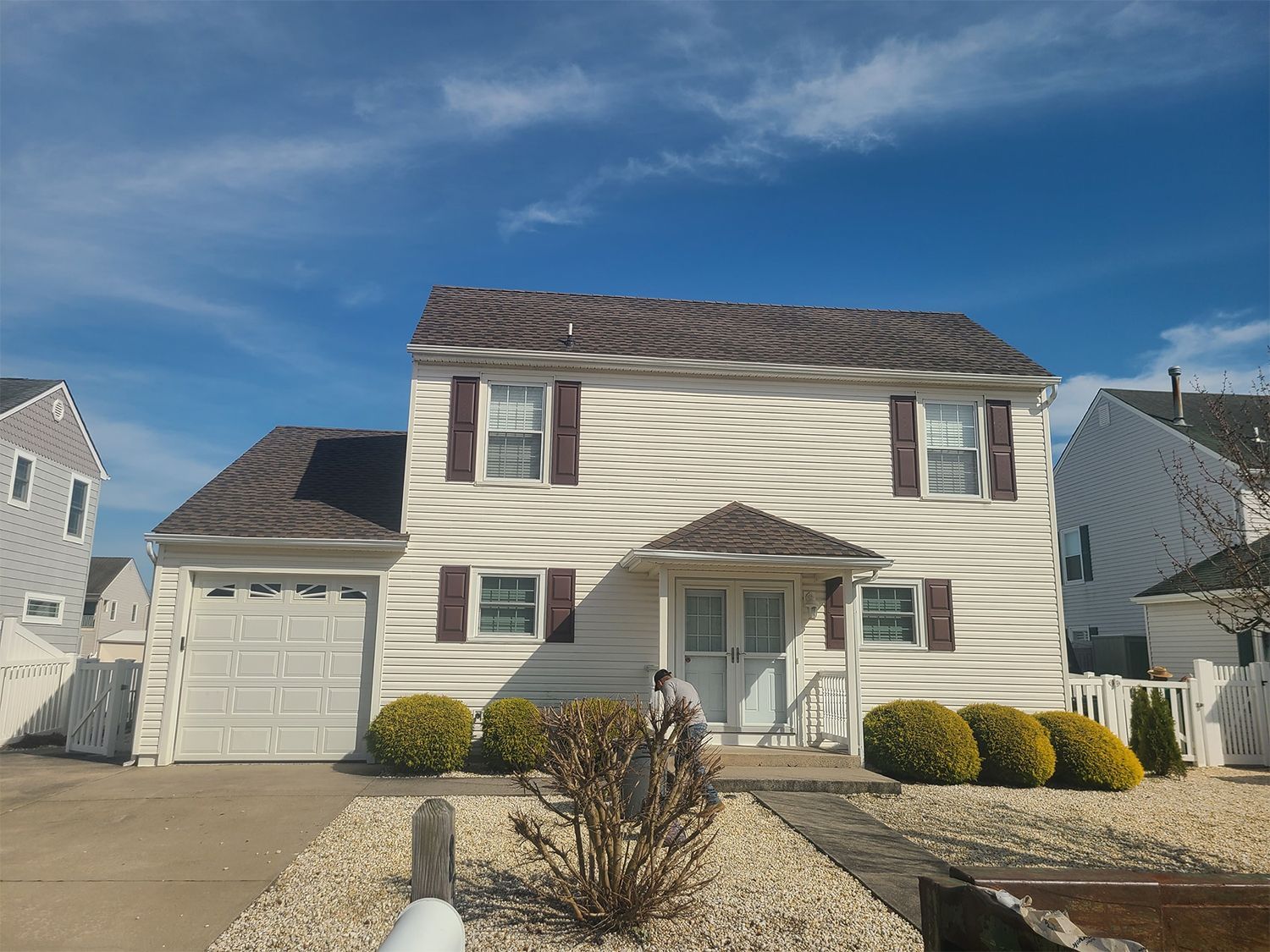A white house with a brown roof and shutters