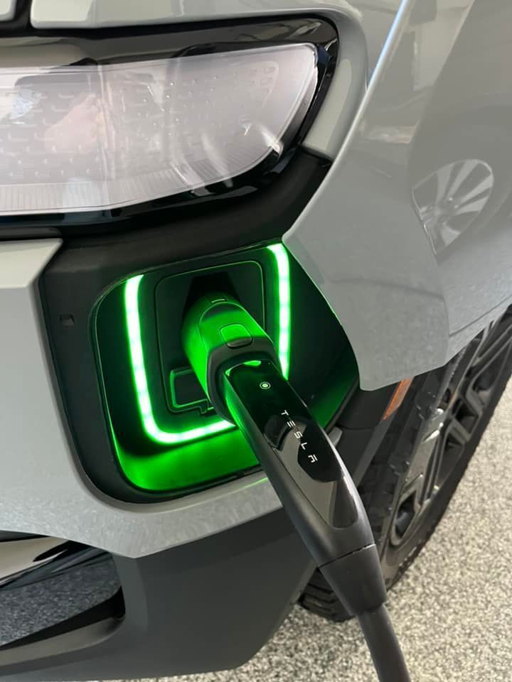 Electric car charging with green glowing port.