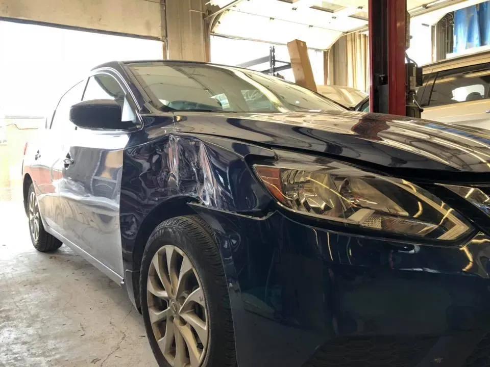 Blue sedan in a garage, viewed from the front-left side.