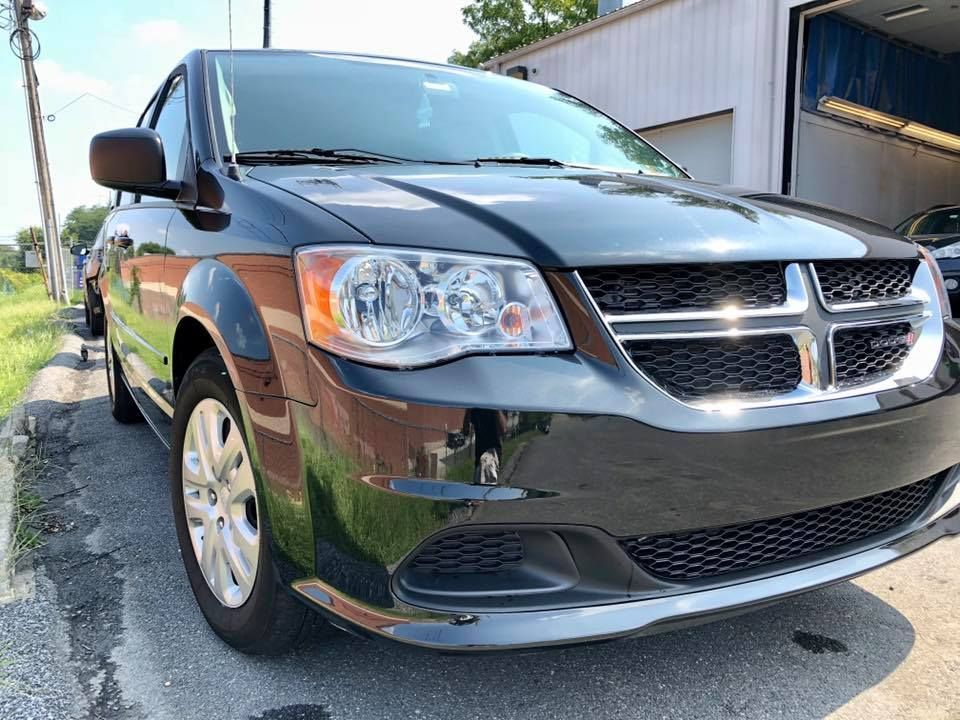 Black Dodge minivan parked outside a building in sunlight