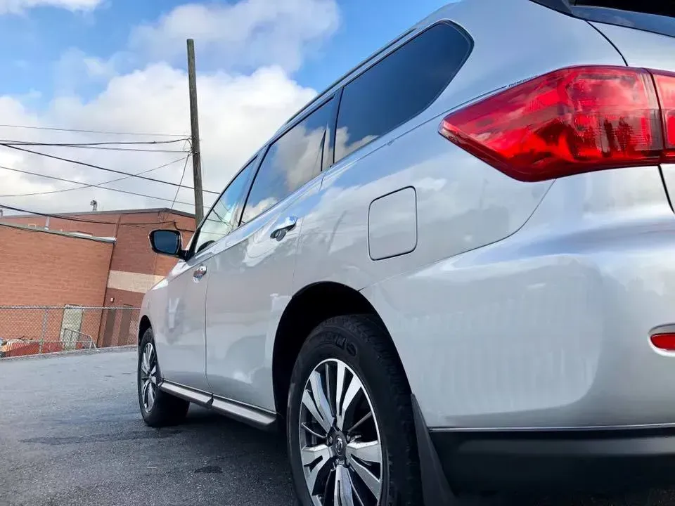 Silver SUV parked beside a brick building under a cloudy sky