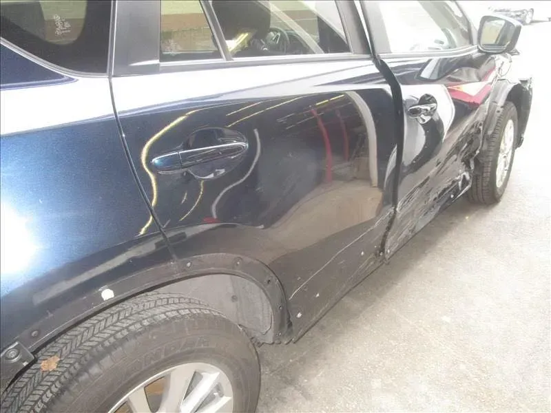 Black SUV with a large dent and scrape on the rear passenger door and quarter panel.
