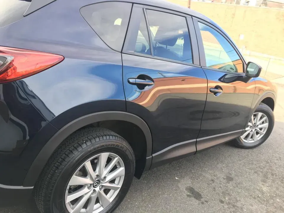 Dark blue SUV parked outdoors, side view with silver wheels and reflections on the door.