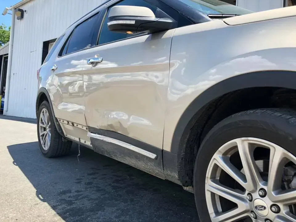 Silver SUV parked beside a building on a sunny driveway
