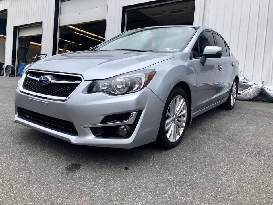 Silver Subaru sedan parked outside a garage on wet pavement