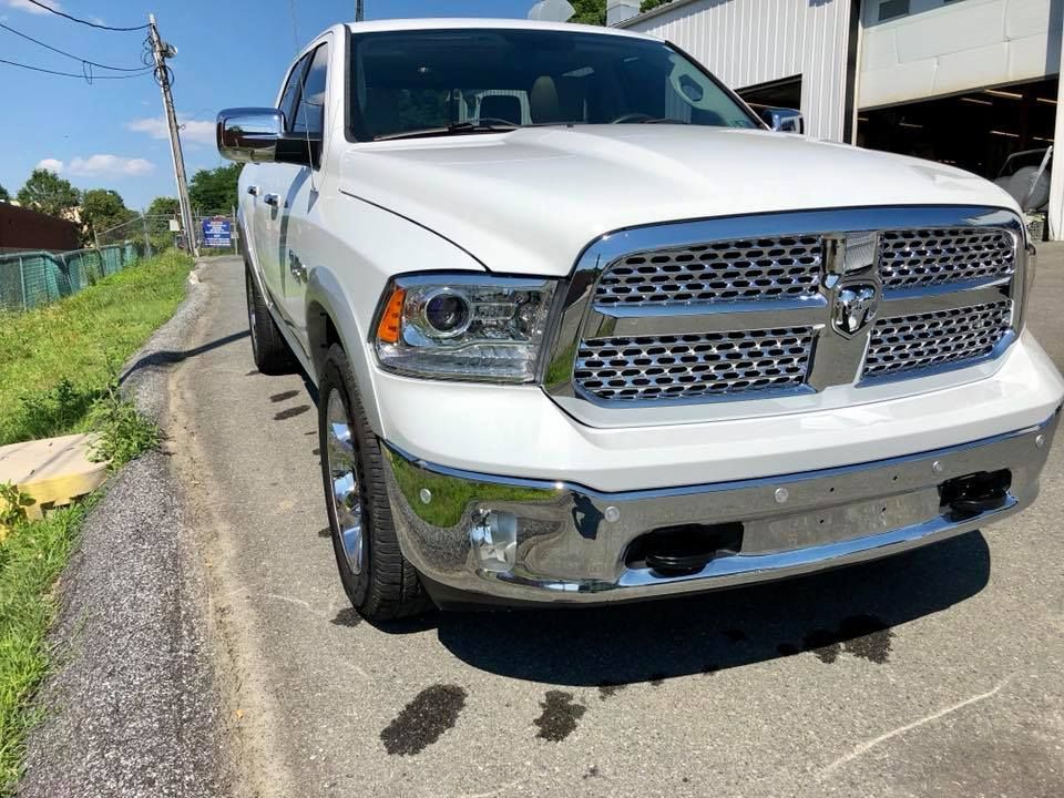 White pickup truck parked on a street beside a building under a clear blue sky