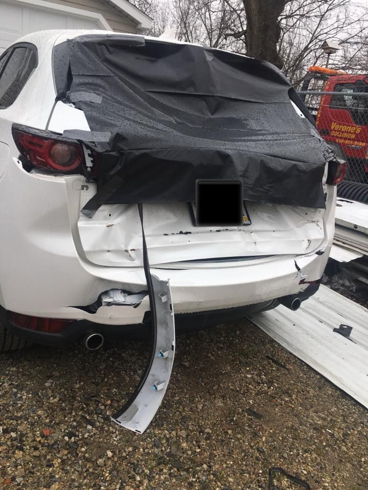 Damaged white SUV with crushed rear hatch and bumper after a collision, parked in snow