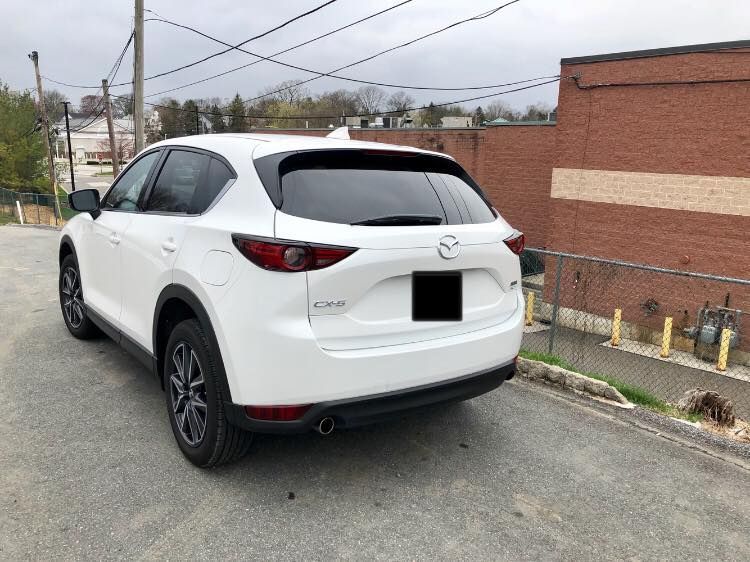 White SUV parked on a street beside a brick building and utility poles.