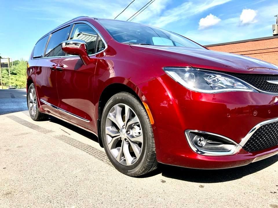 Red minivan parked on a sunny street, front-left view with chrome details.
