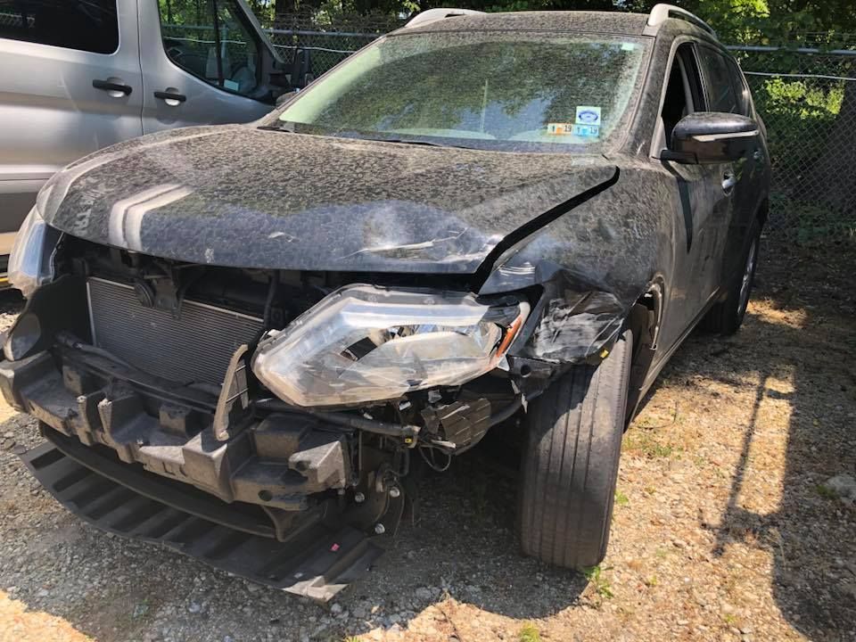 Damaged black SUV with a crushed front end and broken bumper parked outdoors