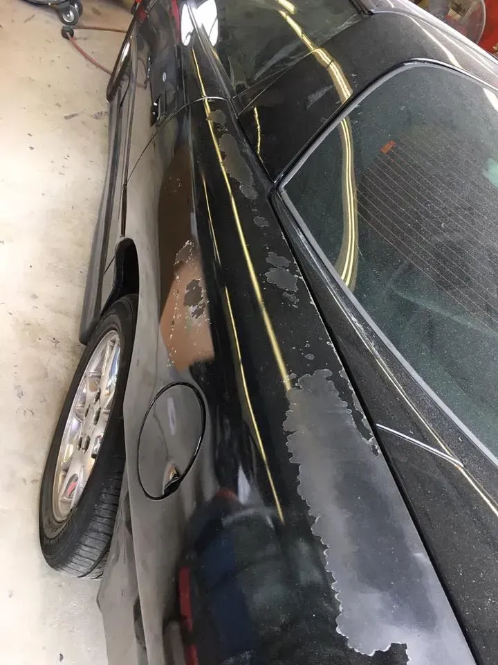 Black sedan parked on its side, showing a damaged roof and chipped paint next to a white car.
