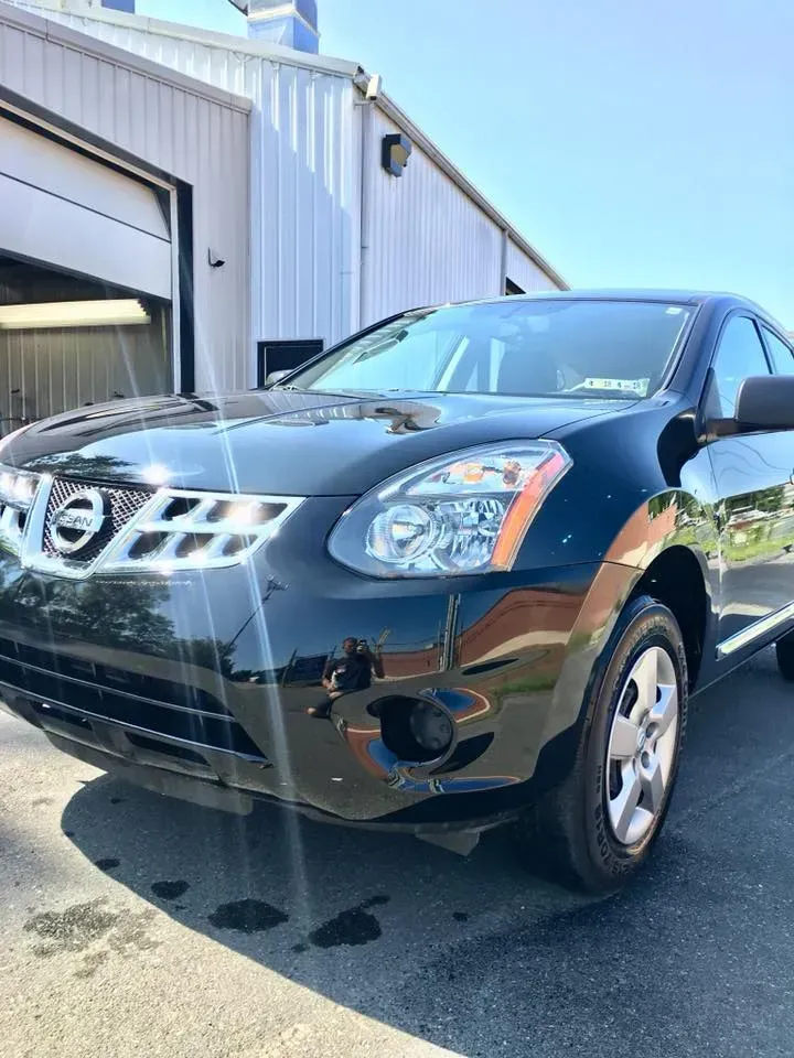 Black Nissan SUV parked beside a garage in daylight