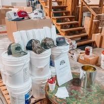 Buckets, hats, and a wooden structure. Hats include baseball caps. The setting is indoors.