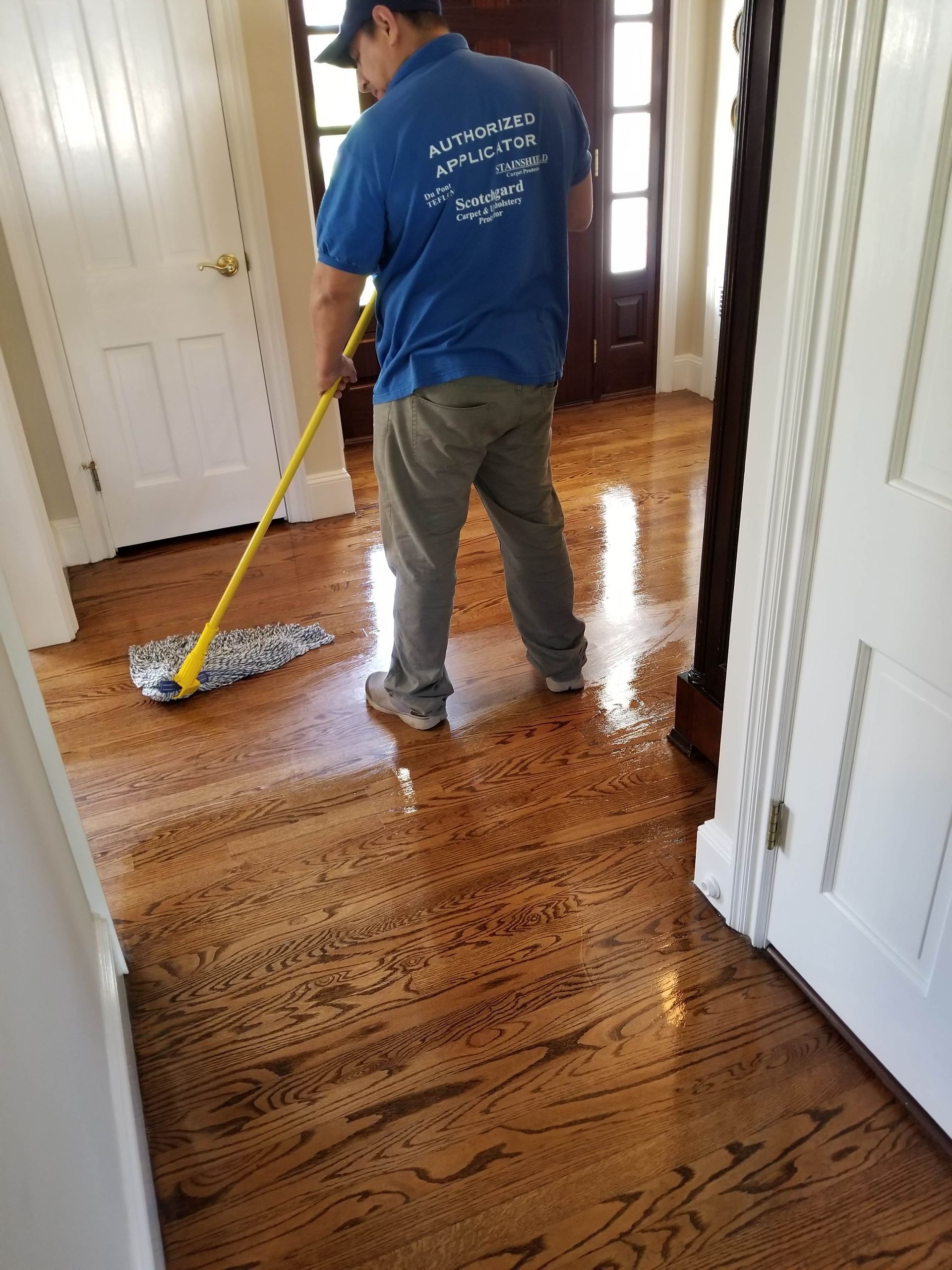 Person mopping a wet hardwood hallway floor in a home