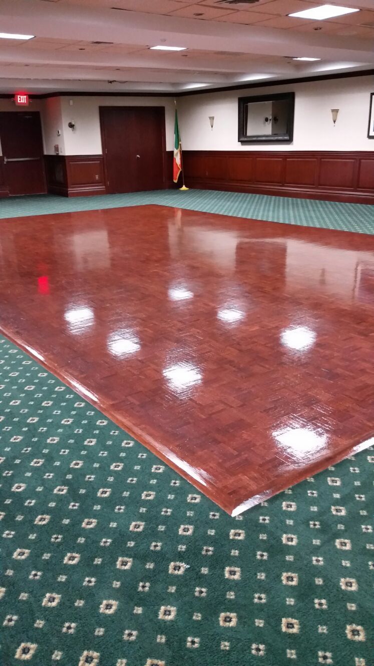 Empty banquet hall with a glossy maroon dance floor and green patterned carpet