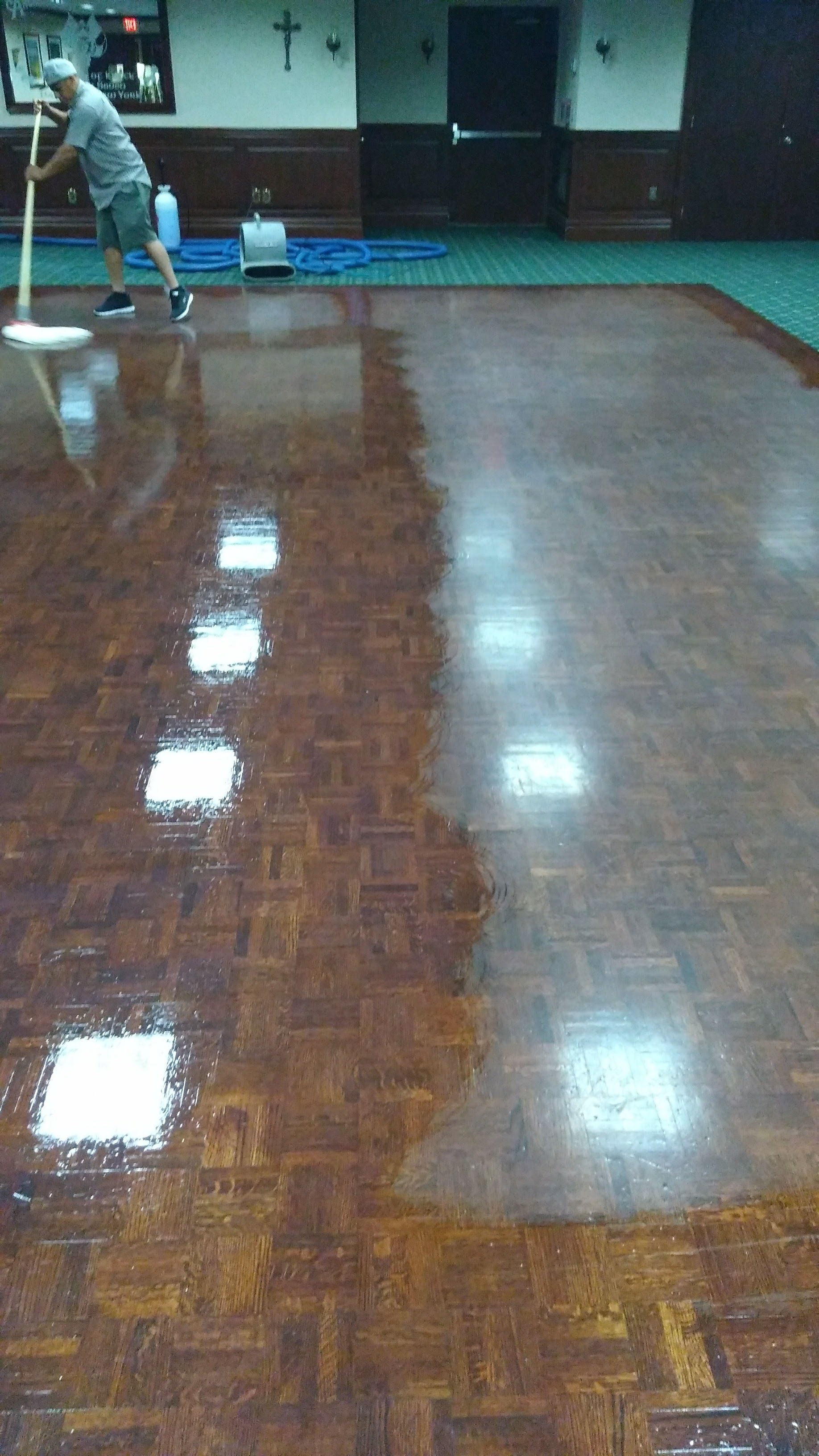 Person mopping a glossy wooden floor in an indoor gym or hall