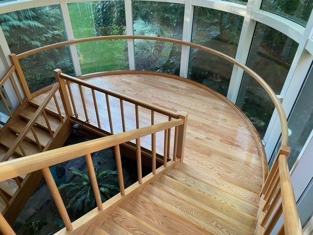 Wooden spiral staircase with light wood, glass windows.