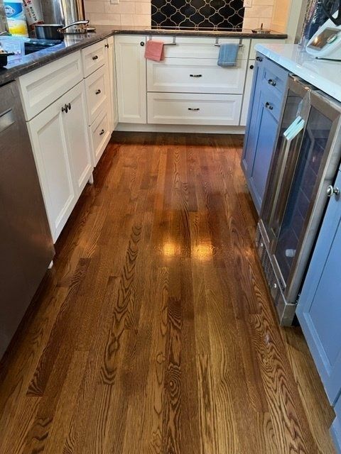 Hardwood floor in a kitchen with white and blue cabinets, stainless steel appliances.