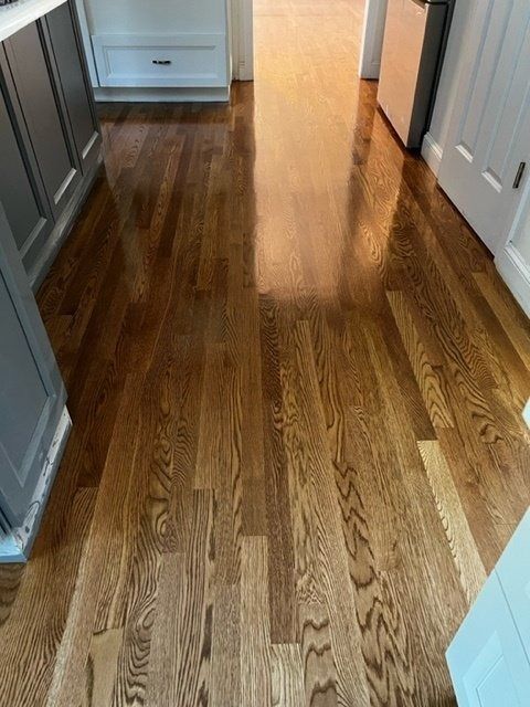 Wood floor with glossy finish, dark brown planks in a kitchen.