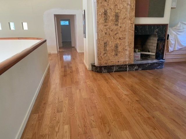 Hardwood floor interior, leading to hallway and fireplace with marble surround.