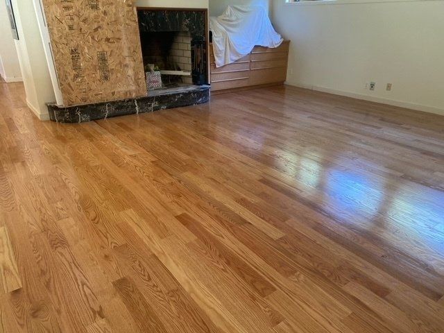 Hardwood floor reflecting light; fireplace on left.