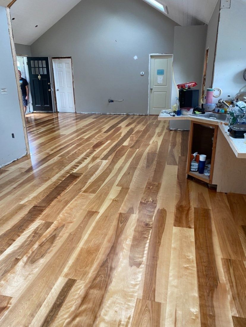Newly installed hardwood floor with varying wood tones in a large, empty room.