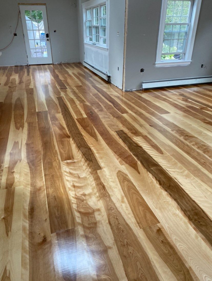 Hardwood floor with varying wood tones in a room with windows and a door.