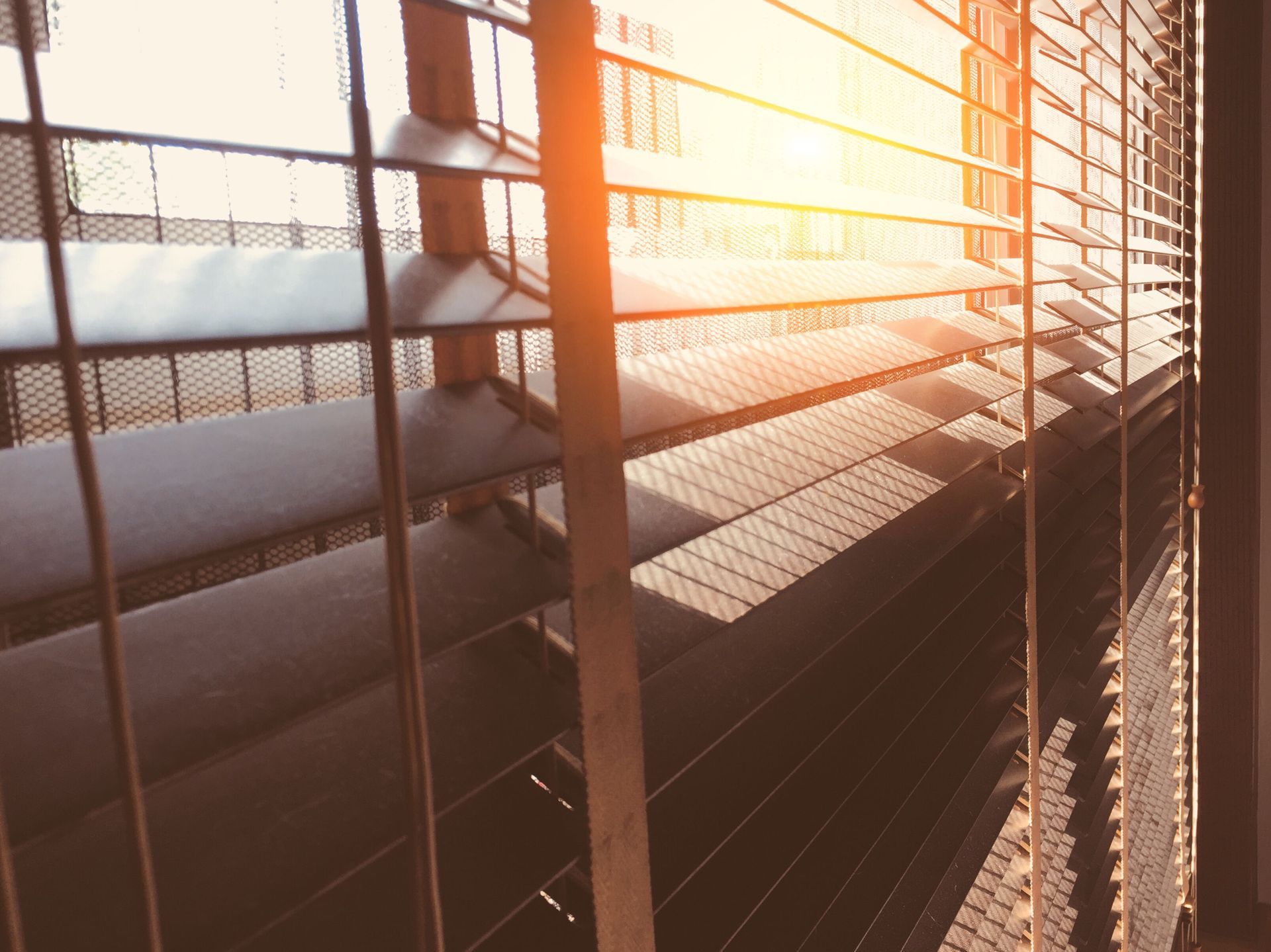 The sun is shining through the blinds of a window.