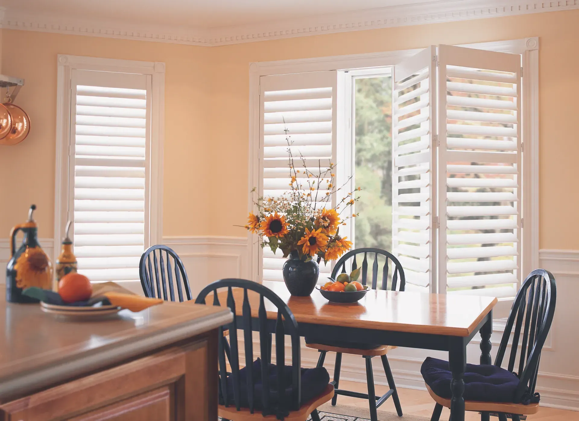 A dining room with a table and chairs and shutters on the windows