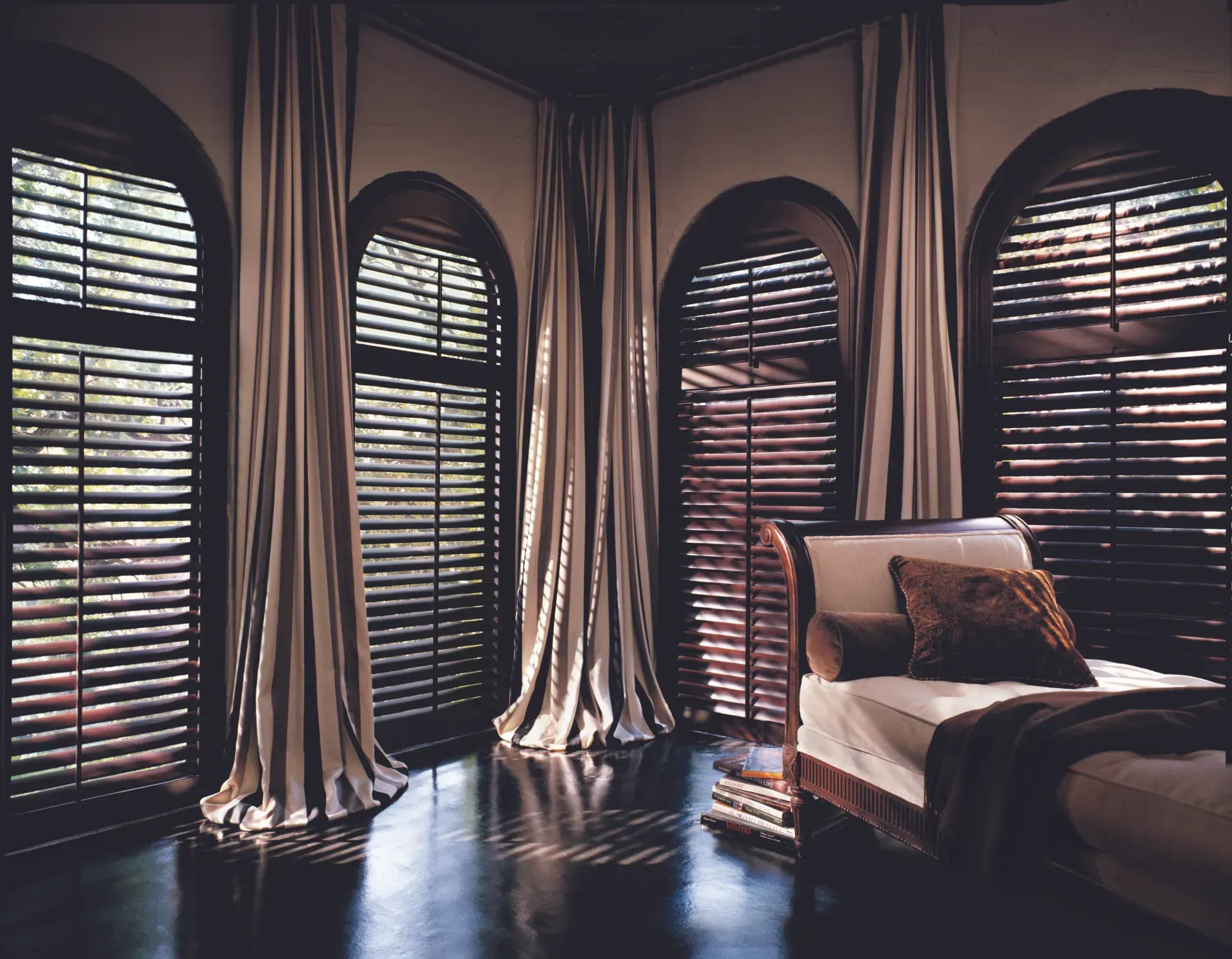 A bedroom with arched windows and wooden blinds