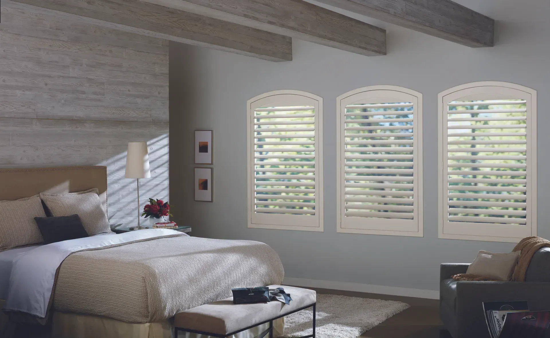 A bedroom with a bed and three windows with shutters