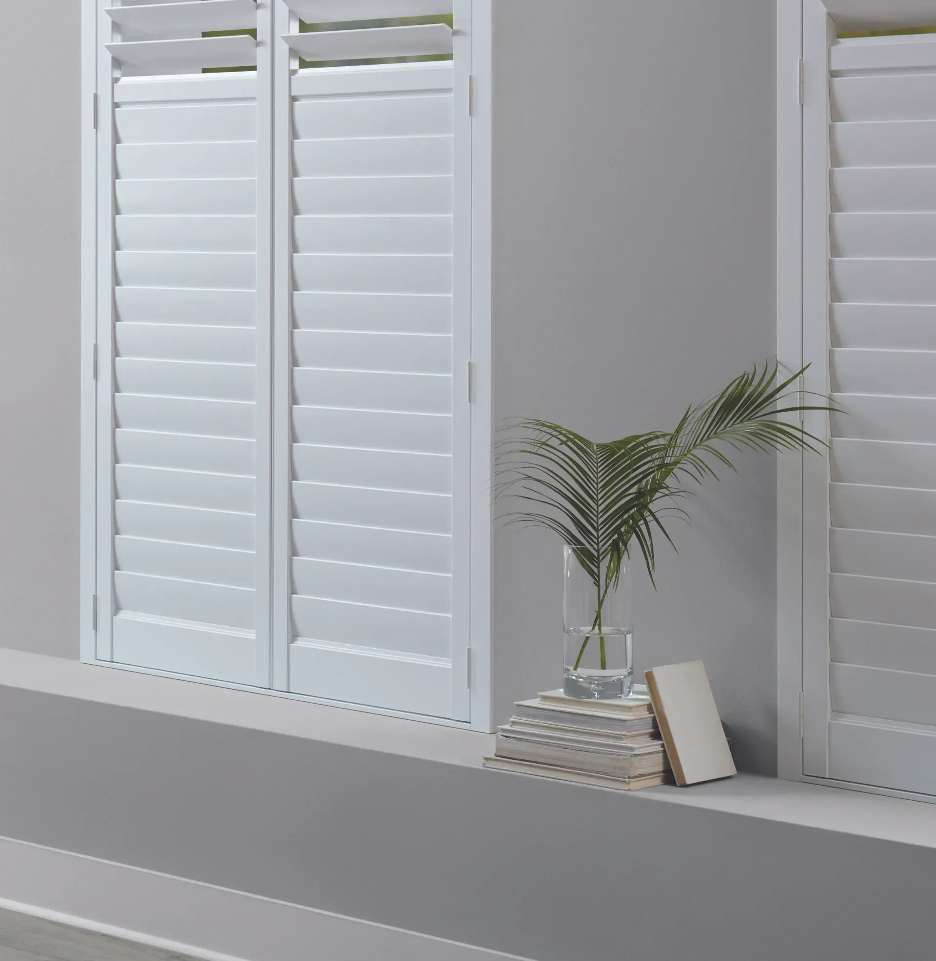A window with white shutters and a plant in a vase