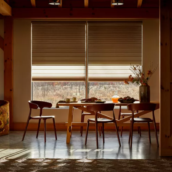 A dining room with a table and chairs in front of a window.
