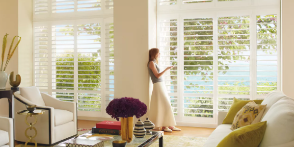 A woman is standing in a living room looking out a window.