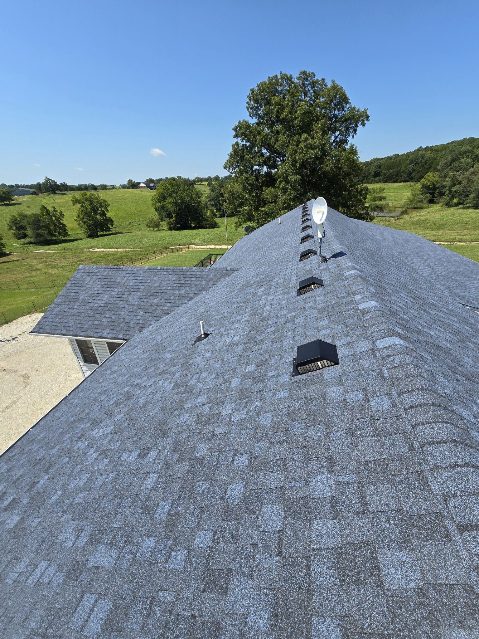 A roof with a lot of shingles on it and a tree in the background.