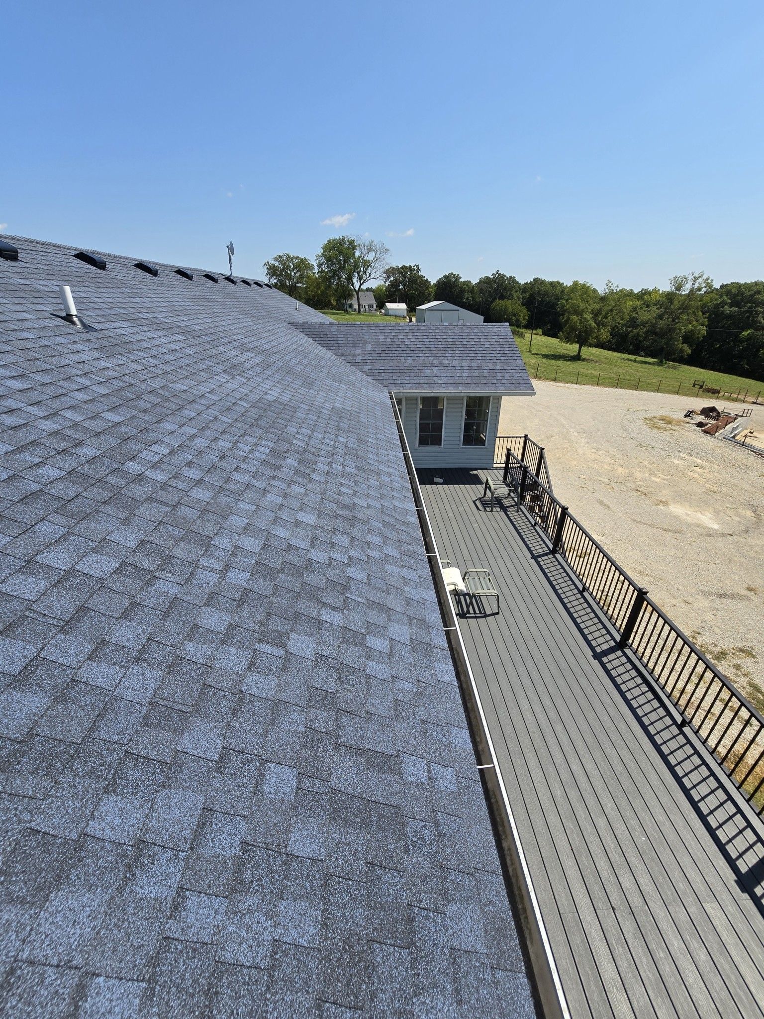 An aerial view of a roof with shingles being installed on a house.