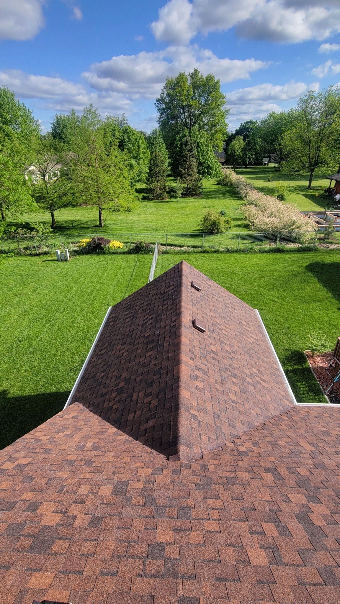 A roof with a pyramid shaped roof and a view of a lush green field.