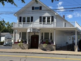 White two-story building with a porch, identified as a funeral home.