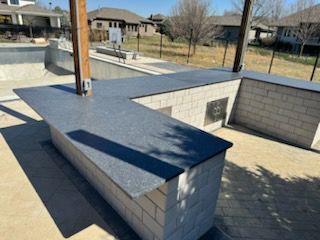 A black counter top is sitting in front of a brick wall.