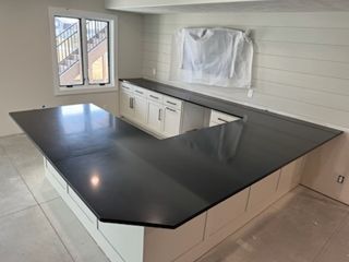 A kitchen with a black granite counter top and white cabinets.