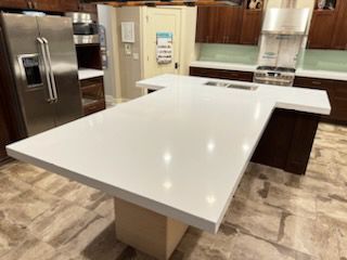 A kitchen with a large white counter top and stainless steel appliances.