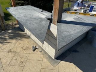 A man is working on a concrete counter top on a patio.