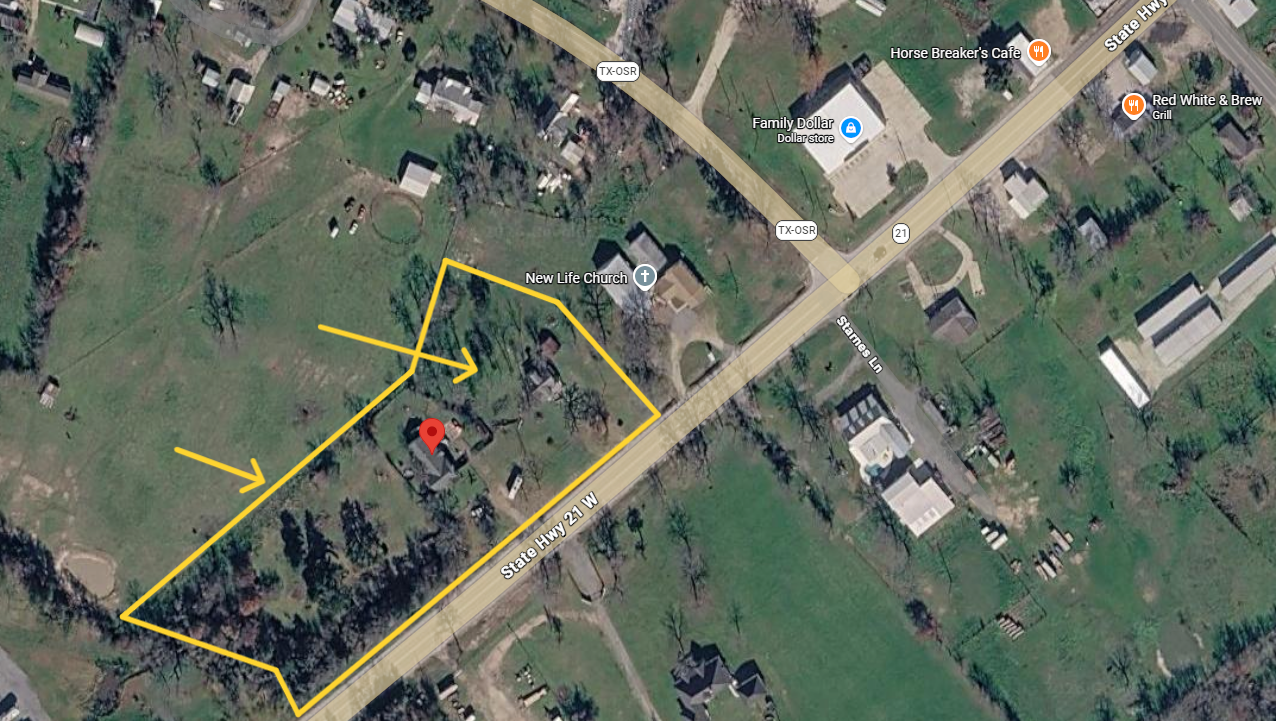 Aerial view of a rural property outlined in yellow with a red marker near a road and scattered houses.