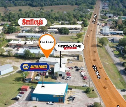 Aerial view of a commercial strip with Smiley's, a for-lease sign, Springtime Roofing, and NAPA Auto Parts